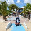 Persona su scooter elettrico su passerella tra palme.