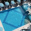 Piscina blu brillante con ombrelloni a righe bianche e blu, vista dall'alto.