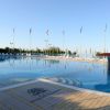 Piscina con bordo piastrellato e bandiere.