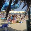 Spiaggia affollata con ombrelloni colorati e bagnanti sotto il sole.
