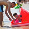 Adulto assistendo un bambino in un gonfiabile al mare.