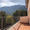Balcone soleggiato con vista montagna alberata.