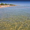 Spiaggia con mare limpido e riflessi del sole.